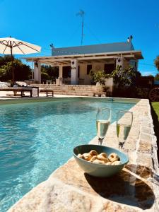 twee glazen champagne naast een schaal schelpen en een zwembad bij Villa 32 Ostuni - Charming House with Pool in Ostuni
