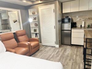 1 dormitorio con 1 cama y 1 silla y cocina en Harmonious Suites en North Miami Beach