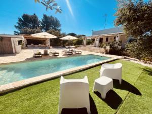 een zwembad met twee witte stoelen in een tuin bij Villa 32 Ostuni - Charming House with Pool in Ostuni