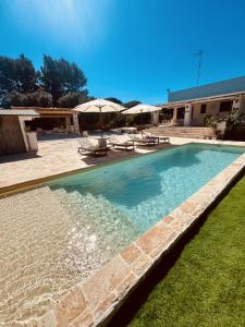 een zwembad in een tuin met parasols bij Villa 32 Ostuni - Charming House with Pool in Ostuni