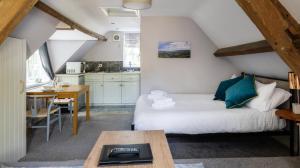 a room with a bed and a table and a kitchen at The Coach House Beautiful Georgian Apartment Wifi and Parking near Bath in Box