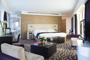 リールにあるホテル バリエール リールのベッドとリビングルームが備わるホテルルームです。