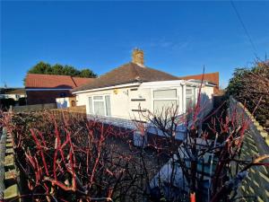 a white house with a chimney on top of a wall at 3 Harbord road in Cromer