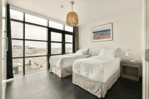 a bedroom with two beds and a large window at Appartement met frontaal zeezicht in Bloemendaal in Bloemendaal