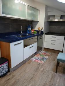 a kitchen with white cabinets and a blue counter top at Ático en Vigo playa Samil in Vigo