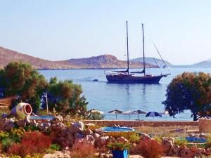 a boat in the water with a beach with umbrellas at Villa Blu Majestic beach villa in Halki