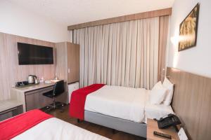 a hotel room with two beds and a desk at Ramada by Wyndham Campinas Viracopos in Campinas +28 photos