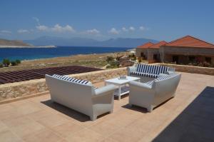 a patio with two chairs and a table and the ocean at Villa Blu Majestic beach villa in Halki