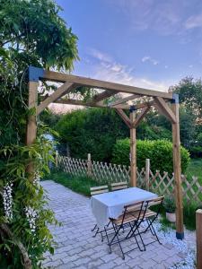 a picnic table and two chairs under a wooden pergola at Exquisite tiny house with garden and air con - between Paris-Disneyland - 3mins from train station in Noisy-le-Grand