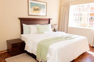 um quarto com uma cama com lençóis brancos e uma janela em Lovely Spacious Two bedroom apartment em Joanesburgo