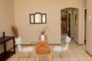 uma sala de jantar com uma mesa de vidro e cadeiras brancas em Lovely Spacious Two bedroom apartment em Joanesburgo