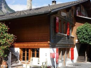 uma casa de madeira com uma porta vermelha e janelas em Darioli 5-Bettwohnung - b48641 em Innertkirchen