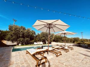 een groep tafels en parasols naast een zwembad bij Villa 32 Ostuni - Charming House with Pool in Ostuni