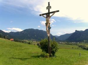 een standbeeld van een vrouw aan een kruis op een veld bij Gemütliche Ferienwohnung in Unterammergau mit Grill und Garten in Unterammergau