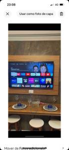 Una pantalla de televisión con una mesa y sillas y una mesa y sillas en Flat araras luxo, en Caldas Novas 2 fotos más