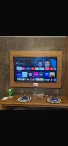Un televisor sobre una mesa de madera con dos vasos. en Flat araras luxo, en Caldas Novas