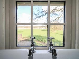 a bathroom sink with two faucets in front of a window at The Lazy Squire by The Water in Rugeley