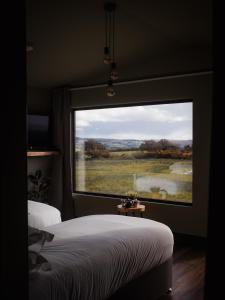 a bedroom with a large window with a view of a field at Wild Hideaways Luxury Lodges and Eco Spa in Bantry
