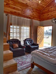 uma sala de estar com duas cadeiras de couro e uma cama em The Kunhar Beach Cottage By Country Club Balakot em Bālākot