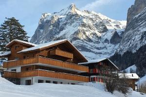un edificio di fronte a una montagna innevata di Velvet Eiger a Grindelwald