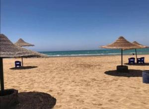 una spiaggia con ombrelloni e sedie e l'oceano di قرية بلولاجون راس سدر شاليه فاخر للايجار a Ras Sedr