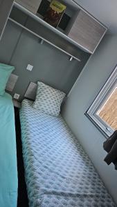 um pequeno quarto com uma cama e uma janela em Mobil home les sables d'or em Cap d'Agde