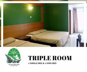 a room with two beds and a green wall at Cool Point Hotel in Tanah Rata