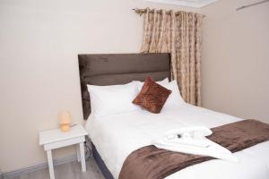 a bedroom with a white bed with a black headboard at 40 on King BnB in East London