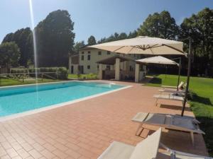 una casa y una piscina con sombrilla y sillas en Ferienhaus mit Privatpool für 27 Personen ca 346 qm in Monsagrati, Toskana Provinz Lucca, en Monsagrati