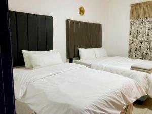 two beds in a hotel room with white sheets at The Plum in Louis Trichardt