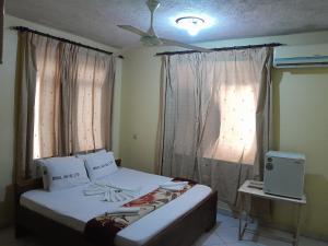 Hotel Ideal في دار السلام: غرفة نوم بسرير ونافذة مع ستائر