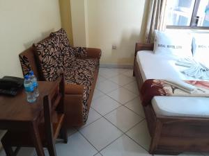 een kamer met een bed, een stoel en een tafel bij Hotel Ideal in Dar es Salaam