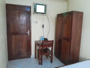 a room with a wooden door and a table and a chair at Hotel Ideal in Dar es Salaam