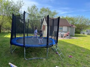two children playing on a trampoline in a yard at Domek Rybaka in Gąski