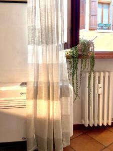 een raam met een wit gordijn naast een radiator bij SanZenoHome StayInVerona Full Apartment in Verona
