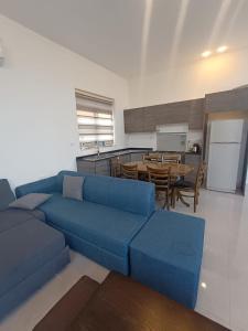 a living room with a blue couch and a kitchen at Airport house in Amman