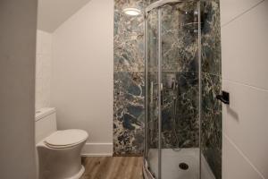 a bathroom with a toilet and a glass shower at One Bedroom Apartment - 3 Minutes from Downtown in Ottawa