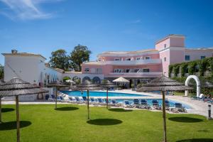 un complejo con piscina y césped con sombrillas en Vila Rosa Flat, en Portimão