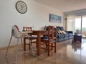 a living room with a table and chairs and a clock at Apartment direkt am Strand in Blanes
