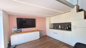 cocina con armarios blancos y TV de pantalla plana en Haus am Weinberg, en Seekirchen am Wallersee