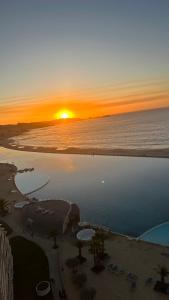 una puesta de sol sobre una playa con puesta de sol en Departamento San alfonso del mar, en Algarrobo