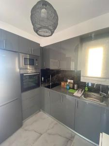 eine Küche mit grauen Schränken, einem Waschbecken und einem Fenster in der Unterkunft Christie's Panorama in Póndi