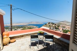 a table and chairs on a balcony with a view of the ocean at Vigli House in Symi