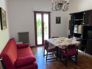sala de estar con mesa y sofá rojo en Montefortino Sibillini House, en Montefortino