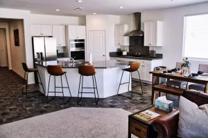 a kitchen with white cabinets and bar stools at Modern Desert Oasis in Coachella
