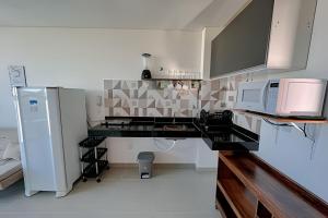 a kitchen with a counter with a microwave and a refrigerator at Flat Kandela - Maracaípe in Porto De Galinhas