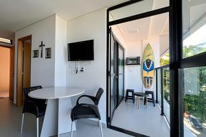 a room with a table and chairs and a surfboard on the wall at Flat Kandela - Maracaípe in Porto De Galinhas