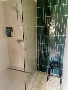 a shower with a stool in a bathroom with green tiles at Patika Vendeghaz in Őriszentpéter