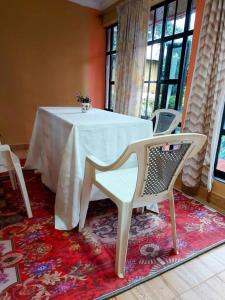 a table with a white table and chairs on a rug at The Orange Cottage in Nyeri