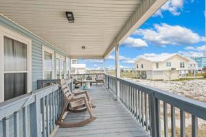 a porch with a rocking chair on the beach at Lucky Enough in Gulf Shores